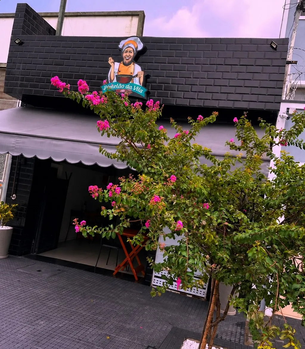 Frente do Panelão da Vila Grill com a placa e a árvore florida